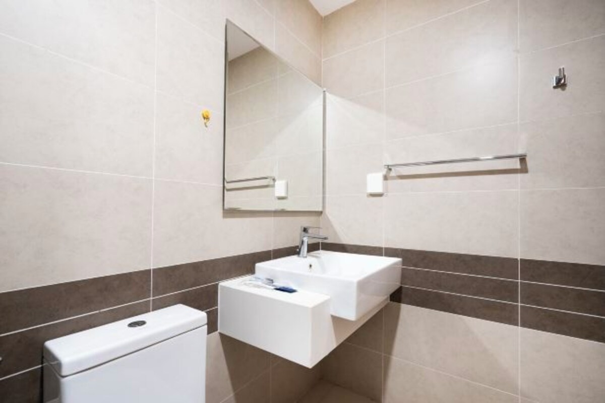 Un bagno moderno con un lavandino bianco, uno specchio e un water.