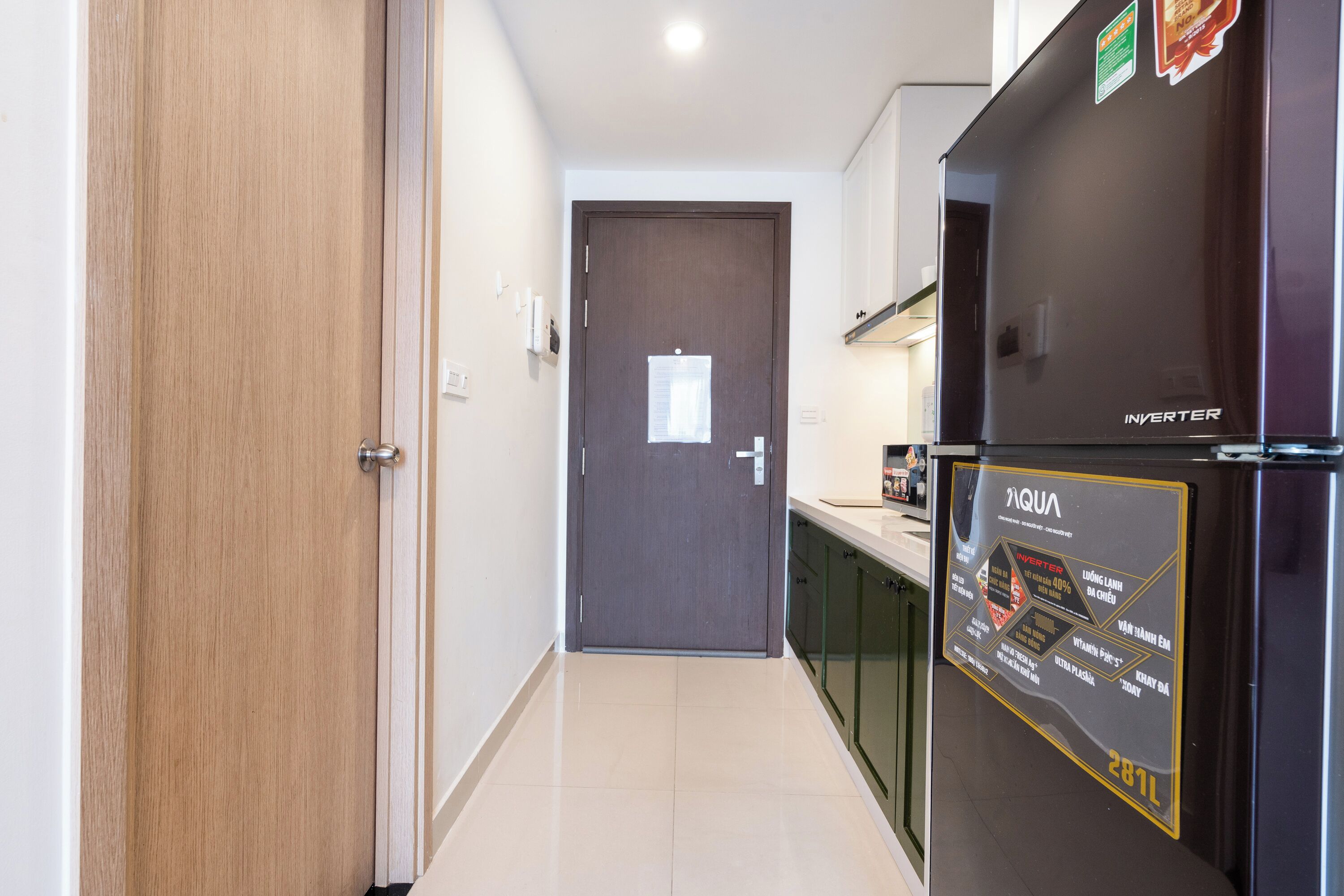 A modern kitchen with a refrigerator, cabinets, and a door with a window.