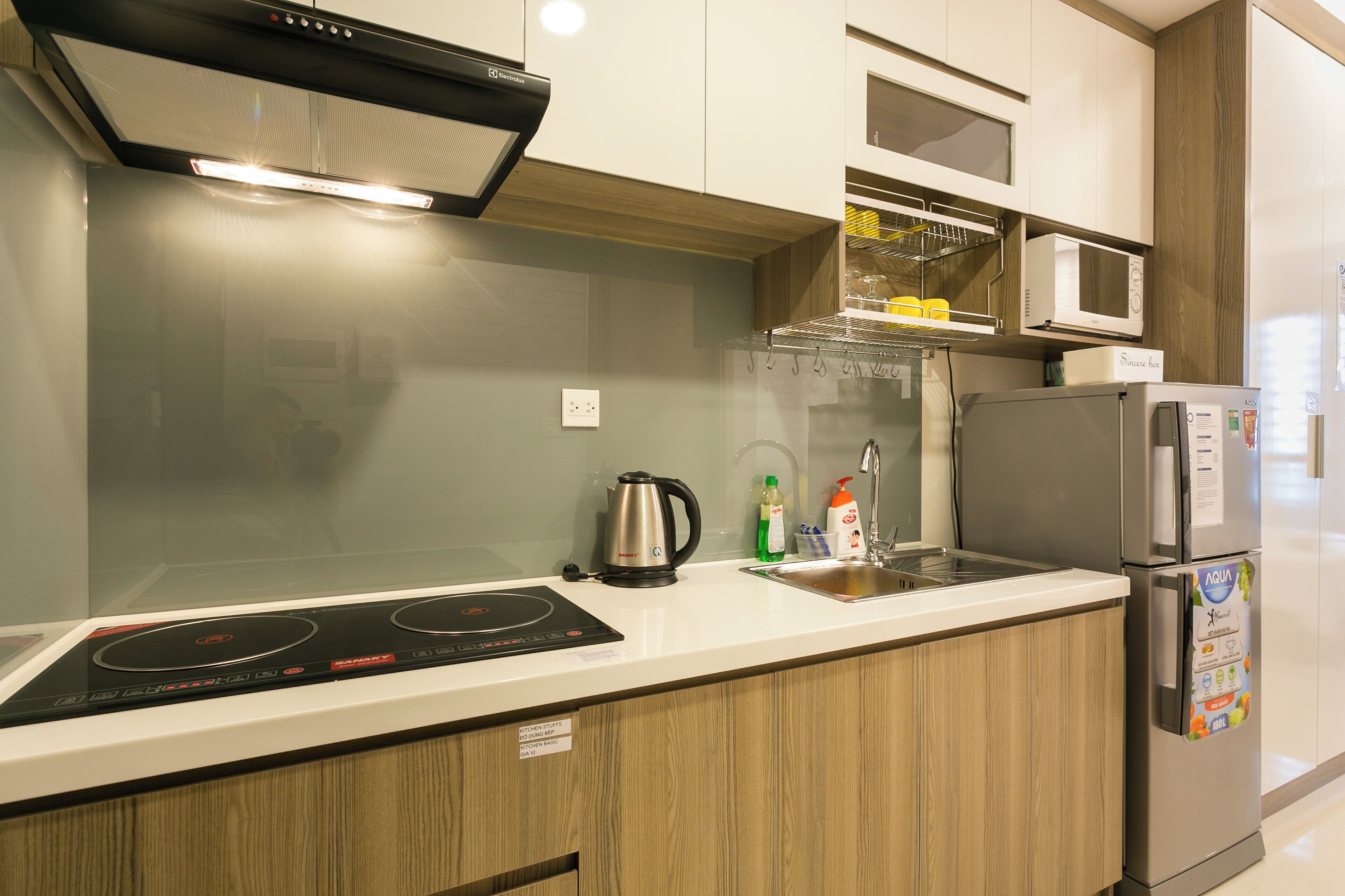 Una cocina moderna con placa de inducción integrada, electrodomésticos de acero inoxidable y armarios de madera.