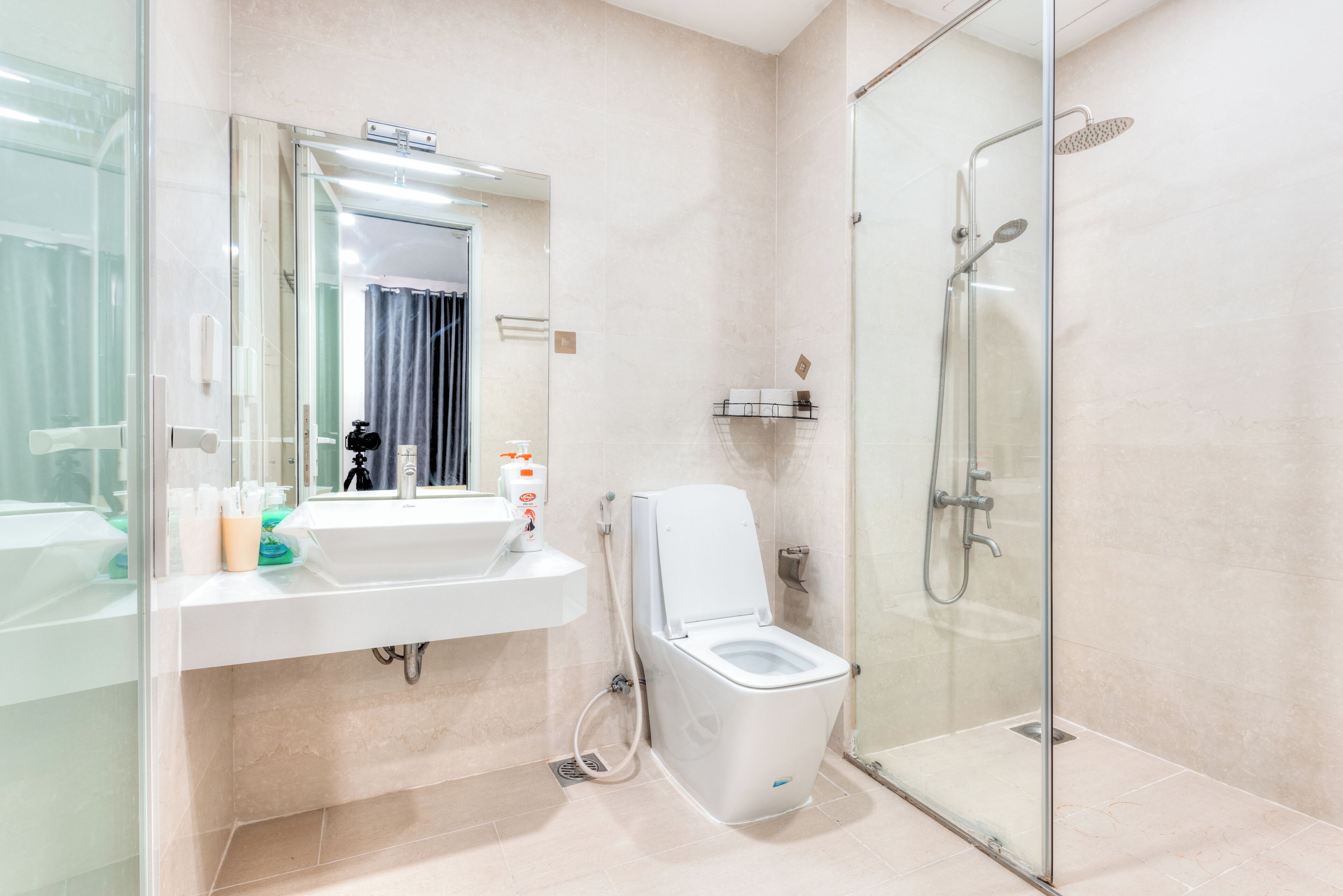 Un baño moderno con cabina de ducha de vidrio, un inodoro blanco y un lavamanos con espejo.