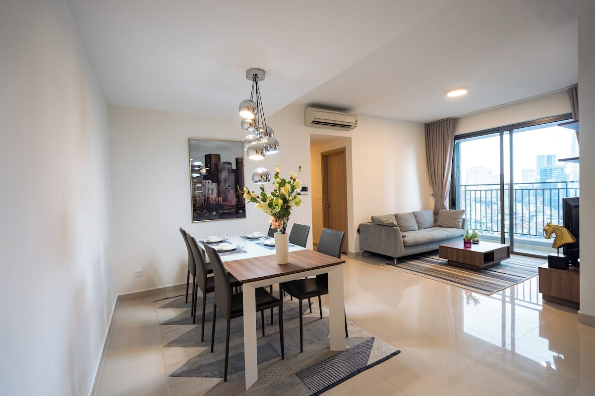 Un salon moderne comprenant un coin repas, un canapé, une table basse et une grande fenêtre donnant sur la ville.