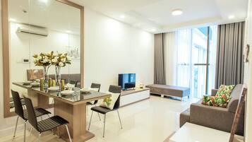 A modern living room with a dining area, a sofa, and a television.