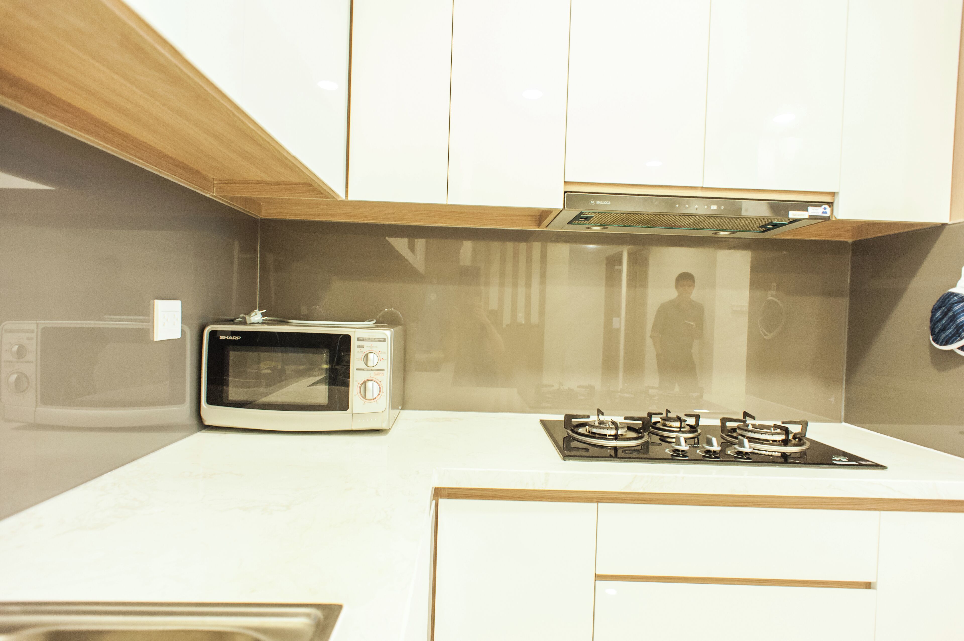 A kitchen with a microwave, a stove, and wooden cabinets.