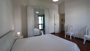 Ein Schlafzimmer mit einem großen Bett, einem Spiegel, einem Sessel und einem Nachttisch mit Lampe.