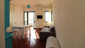 Ein modernes Wohnzimmer mit einer Couch, einem Esstisch mit Stühlen und einem an der Wand befestigten Fernseher.