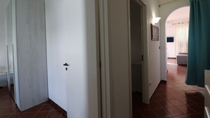 Ein Flur mit einer Holztür, einer weißen Tür und einem türkisfarbenen Vorhang.