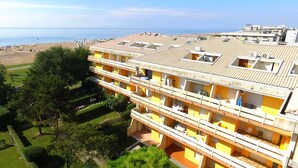 Een meerlaags hotel met balkons, een tuin en uitzicht op het strand en de zee.