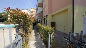 A narrow pathway flanked by buildings, a bicycle, and a fence. - Comfy flat in Rosolina with shared pool (Rosolina Mare)