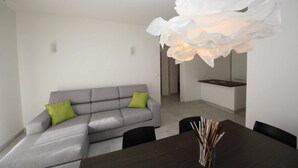 Un comedor moderno con un sofá gris, cojines verdes y una mesa de madera oscura.