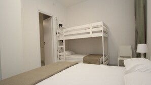 A room with a bunk bed, a bedside table with a lamp, and a chair. - Modern apartment near the beach (Rosolina Mare)