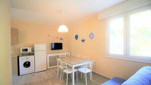 Un espacio habitable compacto con zona de comedor, lavadora, televisor y ventana con vistas.