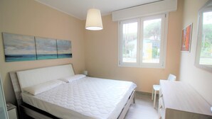 Un dormitorio con cama, mesita de noche y ventana con vistas al exterior.