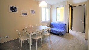 Un área de comedor con una mesa y sillas, un sofá y una puerta.