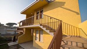 Un edificio amarillo con un balcón y una escalera que sube a los pisos superiores.