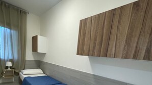 A hotel room with two single beds, a bedside table with a lamp, a wooden headboard, and a window with curtains. - Modern two bedroom apartment near Rosolina beach (Rosolina Mare)