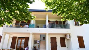 A two-story building with a balcony, a staircase, and a sign indicating it is a restaurant. - Flat with shared garden 200 m from the sea (Rosolina Mare)