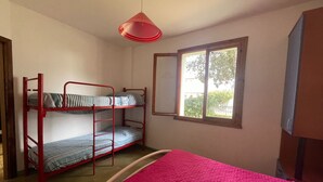 A bunk bed room with a red frame, a pink bedspread, and a window with a view of greenery. - Flat with shared garden 200 m from the sea (Rosolina Mare)