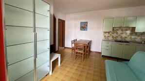 A compact living space with a kitchenette, a dining area, and a sofa. - Accommodation with shared garden close to the sea (Rosolina Mare)