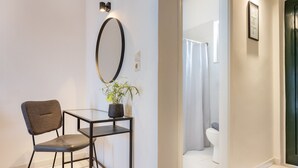 Et moderne badeværelse med toilet, bruser og et glasbord med stol og en potteplante.