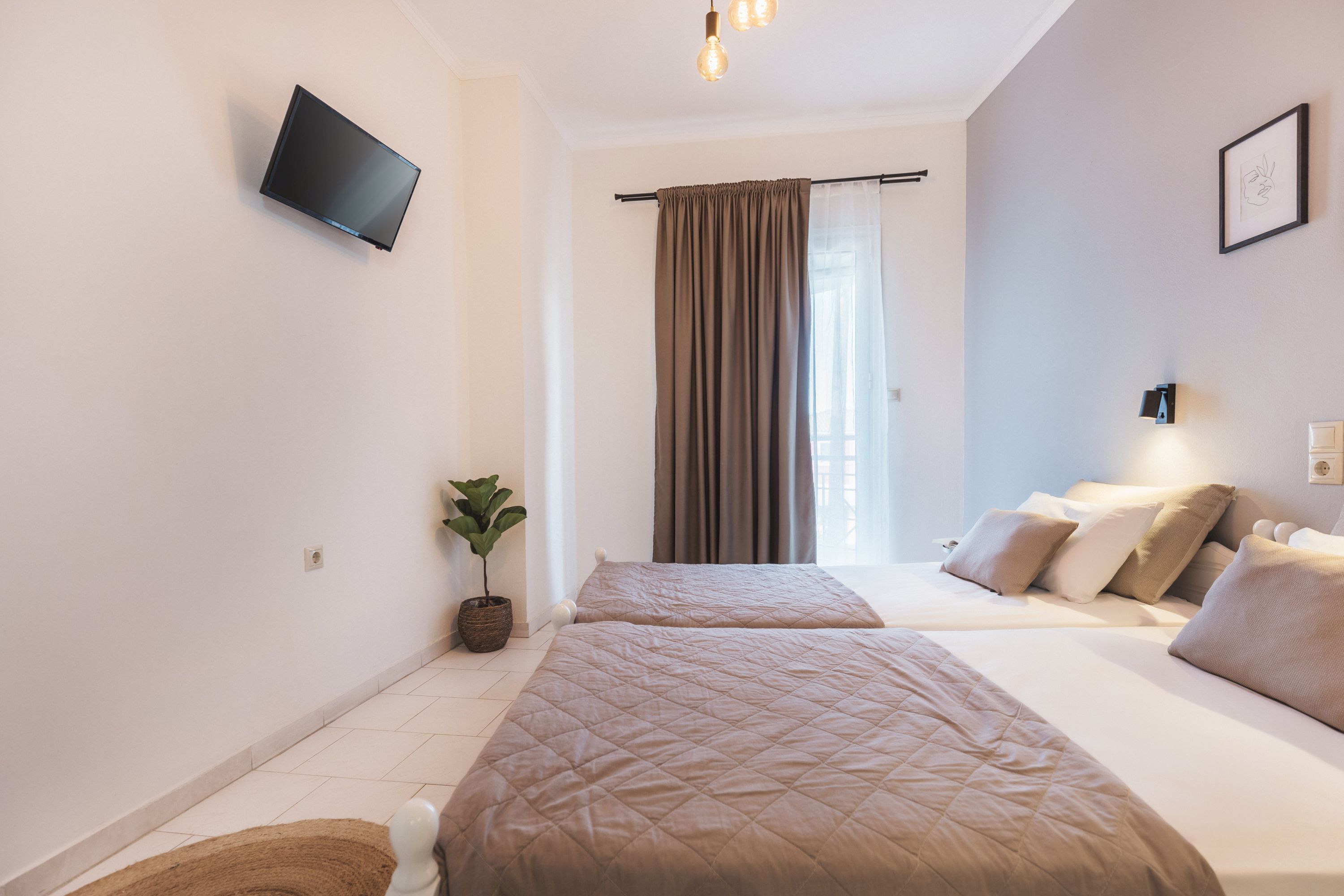 A modern hotel room with two beds, a flat-screen TV mounted on the wall, a potted plant, and a large window with curtains.