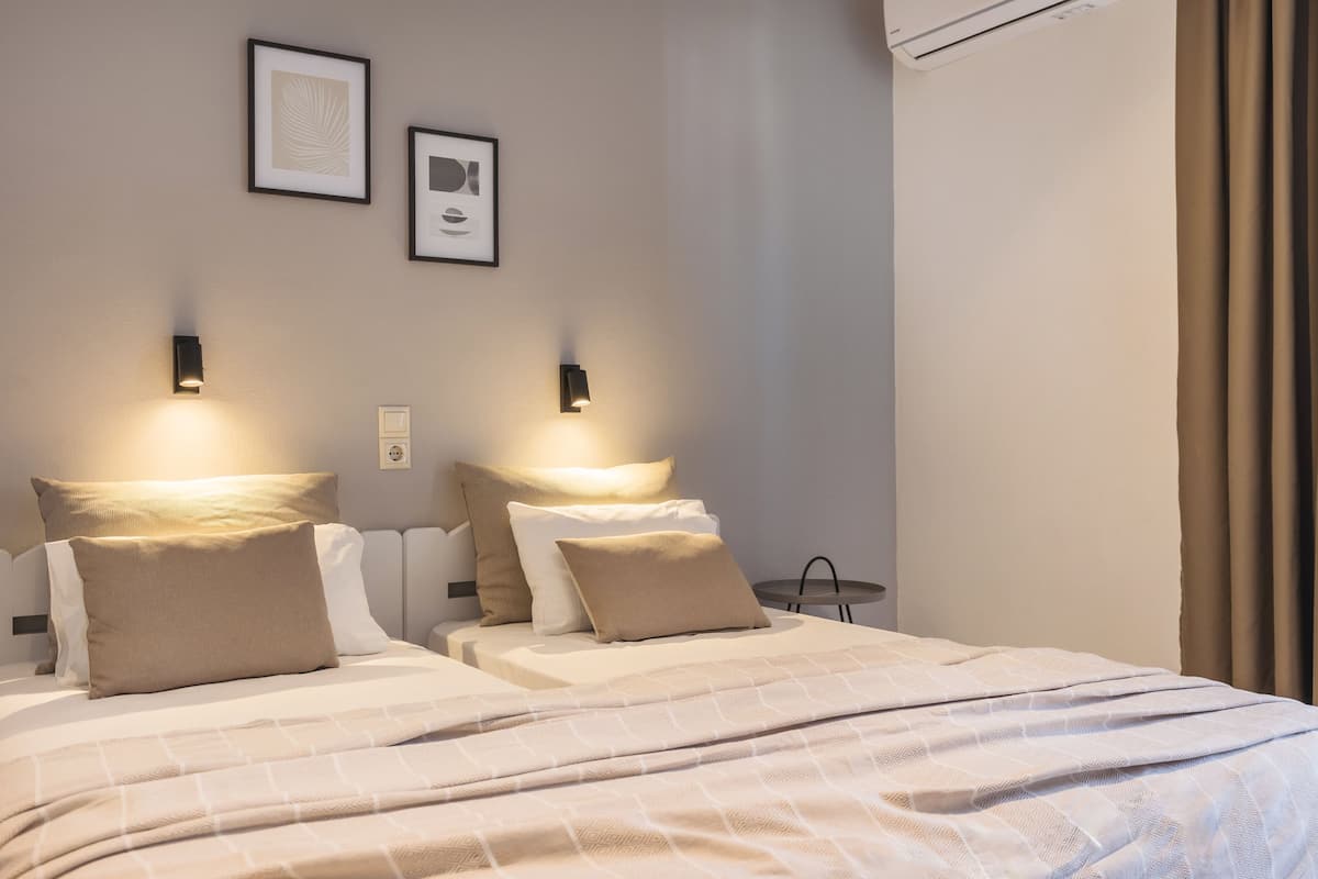 Une chambre d’hôtel avec deux lits, chacun doté d’une tête de lit, d’une table de chevet et d’une lampe fixée au mur.