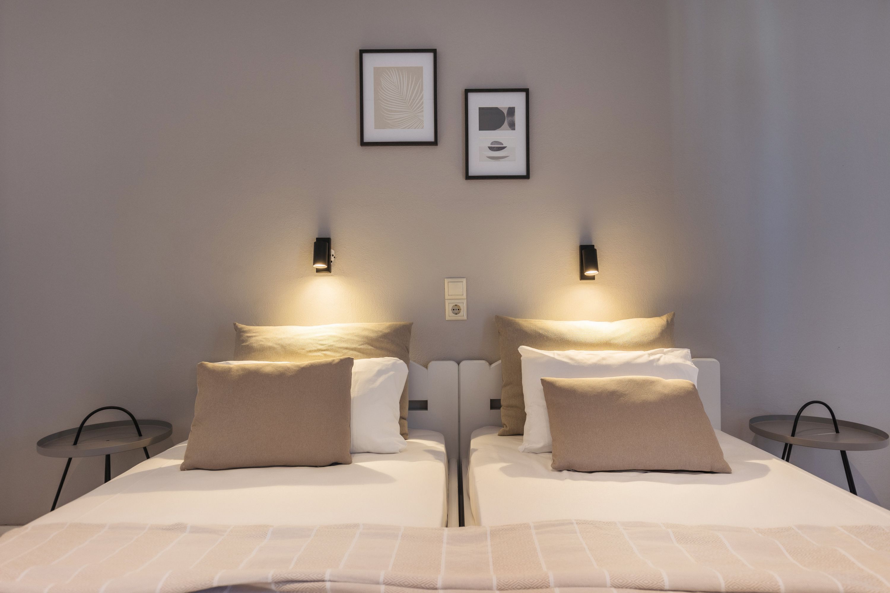 A modern hotel room with a large bed, two bedside tables, and wall-mounted light fixtures.