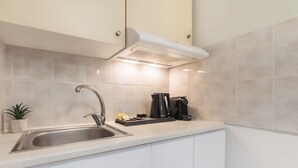 Et moderne køkken med en stålvask, kaffemaskine og elkedel på bordpladen.