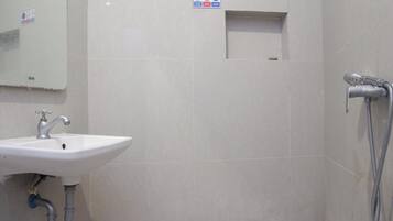 A bathroom with a sink, a mirror, and a shower.