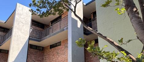 Un edificio moderno de varios pisos con paredes exteriores de ladrillo y concreto, ventanas amplias y un patio con césped.