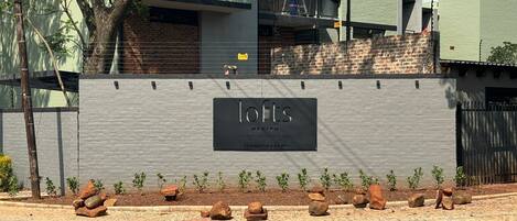 A building with a sign reading "lofts M. Fenyn Furnishing Apartments 76 Umkhosi Rd."