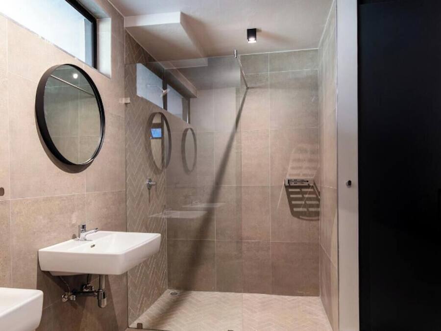 A modern bathroom with a large mirror, a sink, and a shower area.
