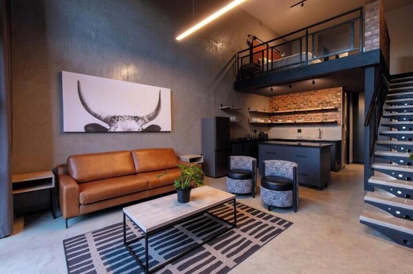 A modern interior with a sofa, coffee table, and a staircase. - Menlyn Lofts (Pretoria)