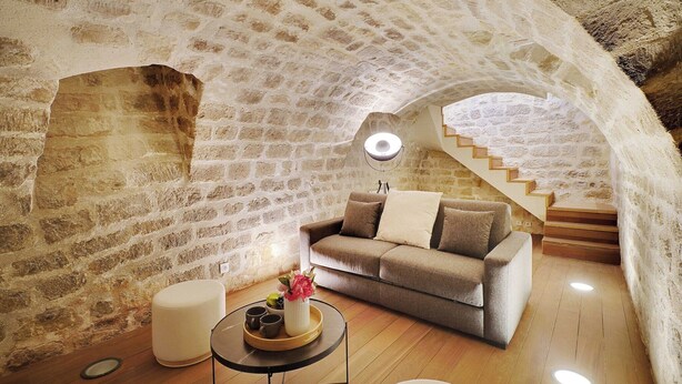 A cozy room with a stone wall, a sofa, a coffee table with a vase, and a staircase. - Chic apartment - 2BR/6P - Saint-Ambroise (Paris)