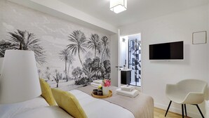 A modern hotel room with a large bed, a wall-mounted TV, and a tropical mural. - Chic apartment - 2BR/6P - Saint-Ambroise (Paris)