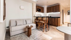 A modern living room with a sofa, a small round table, and a dining area with wooden chairs. - Elegant apartment - 1BR/4P - Rue Saint-Honoré (Paris)