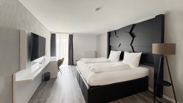 Una camera d'albergo moderna con un letto grande, una scrivania e una televisione.