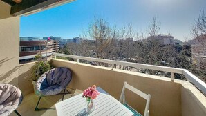 A balcony with a white table, a chair, and a potted plant. - Studio Azur, terrace, parking, 10min from sea (Fréjus)