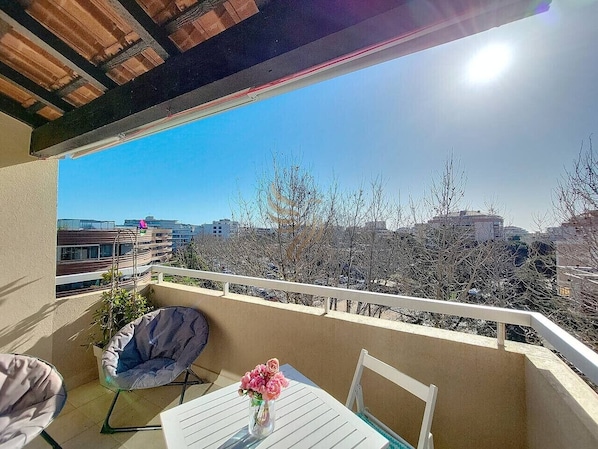 A balcony with a white table, a chair, and a potted plant.