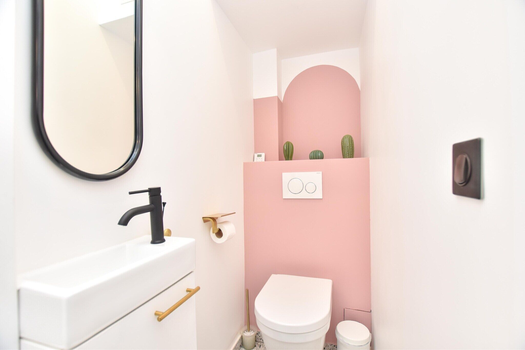 A bathroom with a white sink, black faucet, and a toilet.