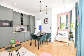 A modern kitchen with grey cabinets, a dining area with a table and chairs, and a cozy seating area with a sofa and a small side table.