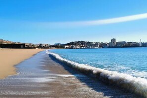 A beach with a clear view of the shoreline and a distant cityscape. - T2,garage,AC,swimming pool,750 m from the beach. (Fréjus)