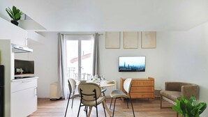 Un salon moderne comprenant un coin repas, une cuisine et un téléviseur fixé au mur.