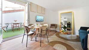 Un salon moderne avec un coin repas, un grand miroir et une vue sur l’extérieur.