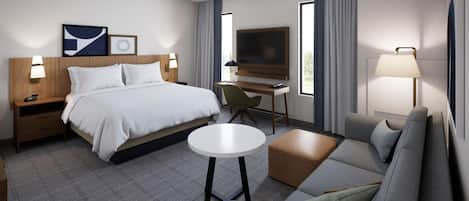 Ein modernes Hotelzimmer mit Bett, Schreibtisch, Fernseher, Sofa und kleinem Tisch.