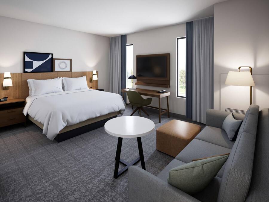Een moderne hotelkamer met een bed, een bureau, een televisie, een bank en een klein tafeltje.