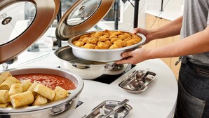 Een buffetopstelling met diverse gerechtjes, waaronder gebakken snacks en een schaal saus.