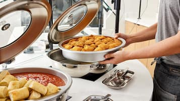 Ein Buffet mit verschiedenen Speisen, darunter eine Schüssel mit frittierten Snacks und eine Soße.