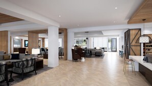 Un vaste espace de vie moderne, doté d’un parquet en bois disposé en point de Hongrie, d’un canapé aux motifs en point de Hongrie et d’un coin repas avec une table à plateau en verre.