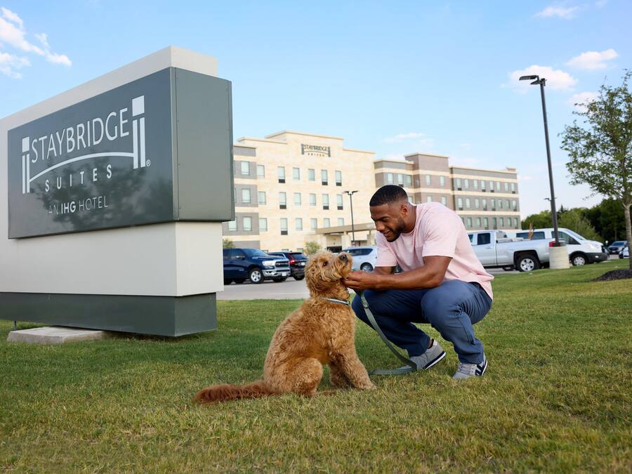 A Staybridge Suites sign in front of a building with a clear sky.