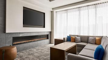 A modern living room with a flat-screen TV mounted above a fireplace, a sectional sofa with cushions, and a coffee table.